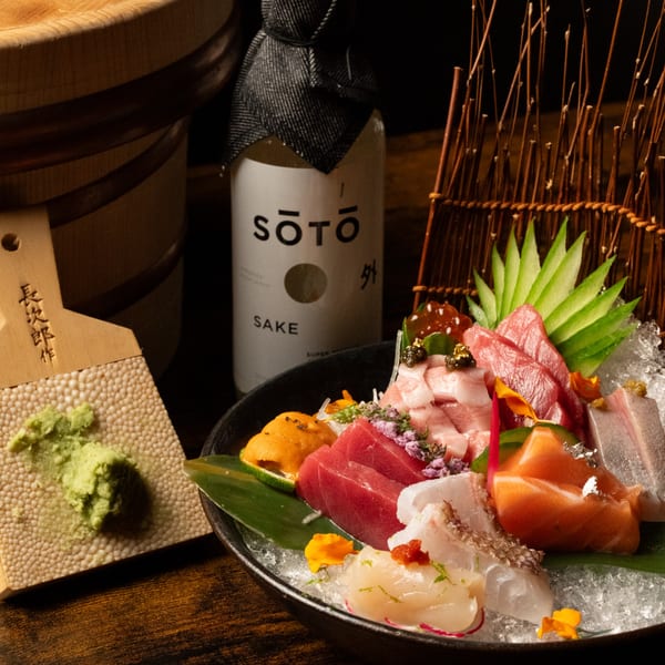 A Kase Sake & Sushi platter of sashimi, uni, and roe, with wasabi and a sake bottle.
